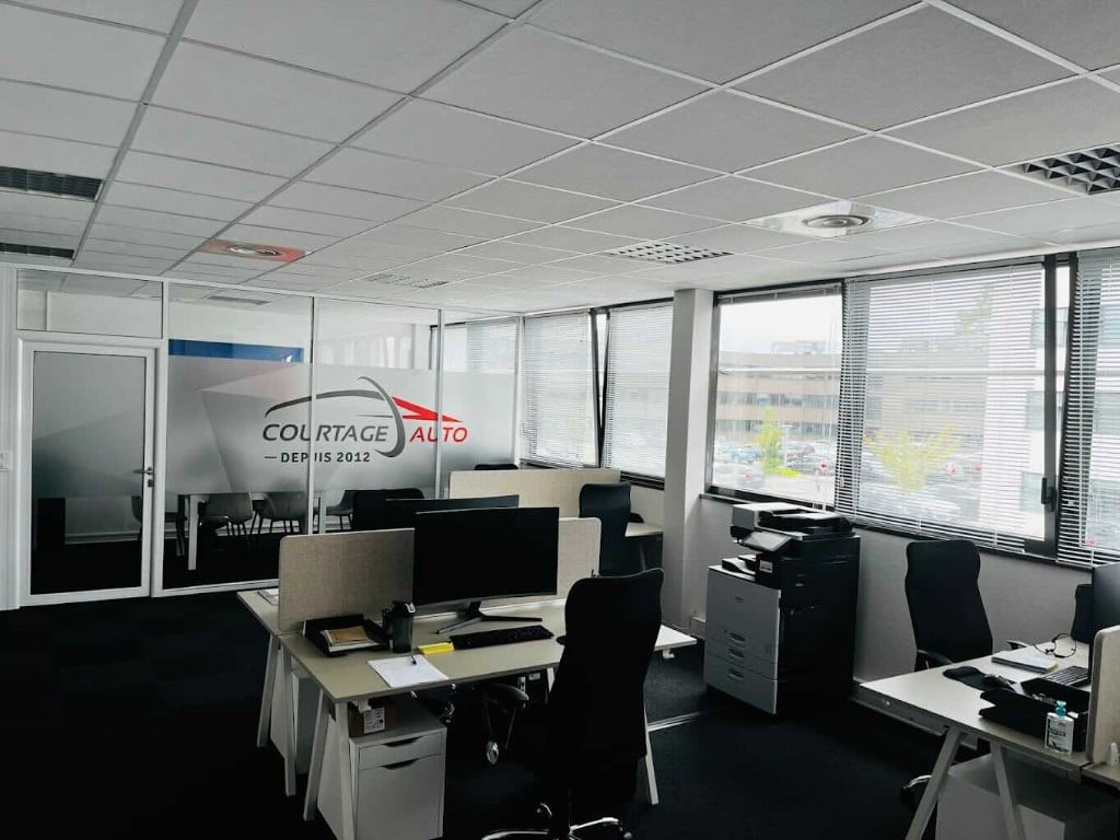 Intérieur des bureaux de l'agence Courtage Auto Bordeaux à Pessac, avec postes de travail et imprimante